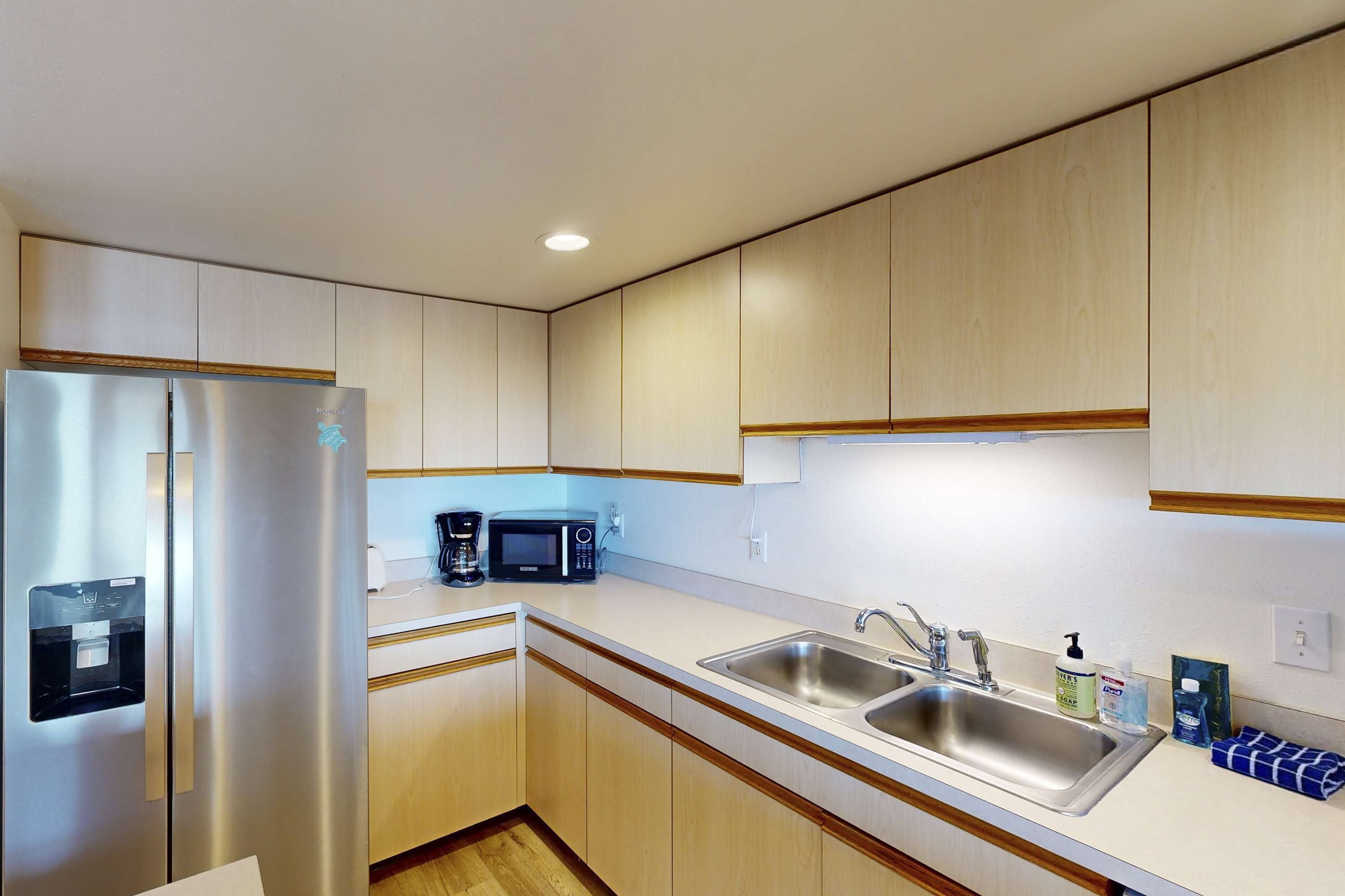A modern kitchen with stainless steel appliances, wooden cabinets, and a double sink.