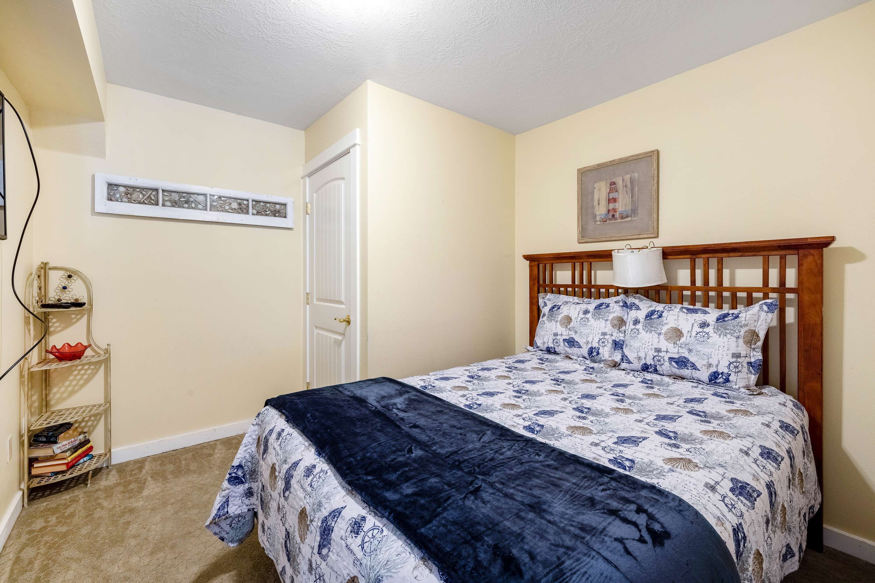 Camera da letto con un letto, una testiera in legno, un comodino, una lampada e uno scaffale con libri e oggetti decorativi.