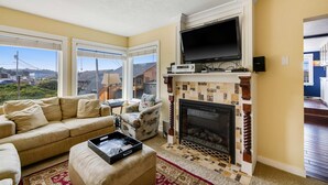 Una sala de estar con chimenea, un sofá, un televisor y un ventanal grande.
