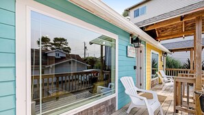 A covered deck with white plastic chairs and a wooden railing. - Ocean view cabin with deck and beach access dog friendly (Depoe Bay)