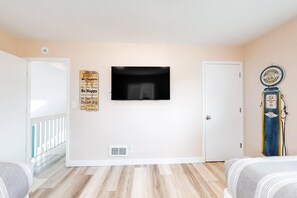 A bedroom with a bed, a television mounted on the wall, a vintage gas pump decoration, and a door. - Enchanting home near the coast with hot tub full kitchen and washer dryer (Gleneden Beach)