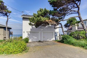 A two-story house with a garage, surrounded by greenery and a clear sky. - Dog friendly home with oceanfront location and fireplace walk to the beach (Gleneden Beach)