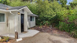 Una casa pequeña de un piso con una terraza de madera y un buzón.
