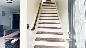 Una escalera de madera con barandilla que lleva a una puerta con un panel de vidrio.