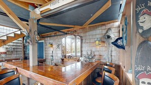 Zona de bar con barra de madera pulida, sillas de madera y decoración náutica.