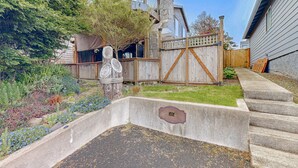 Un patio trasero con una jardinera de concreto, una valla de madera y una casa con fachada de piedra.