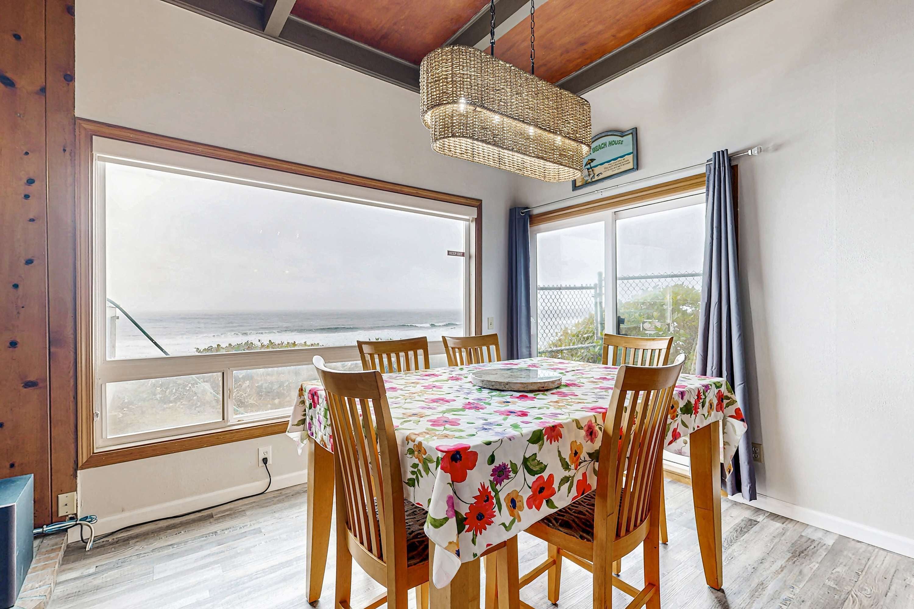 A dining area with a table set for four, large windows with a view, and a hanging light fixture.