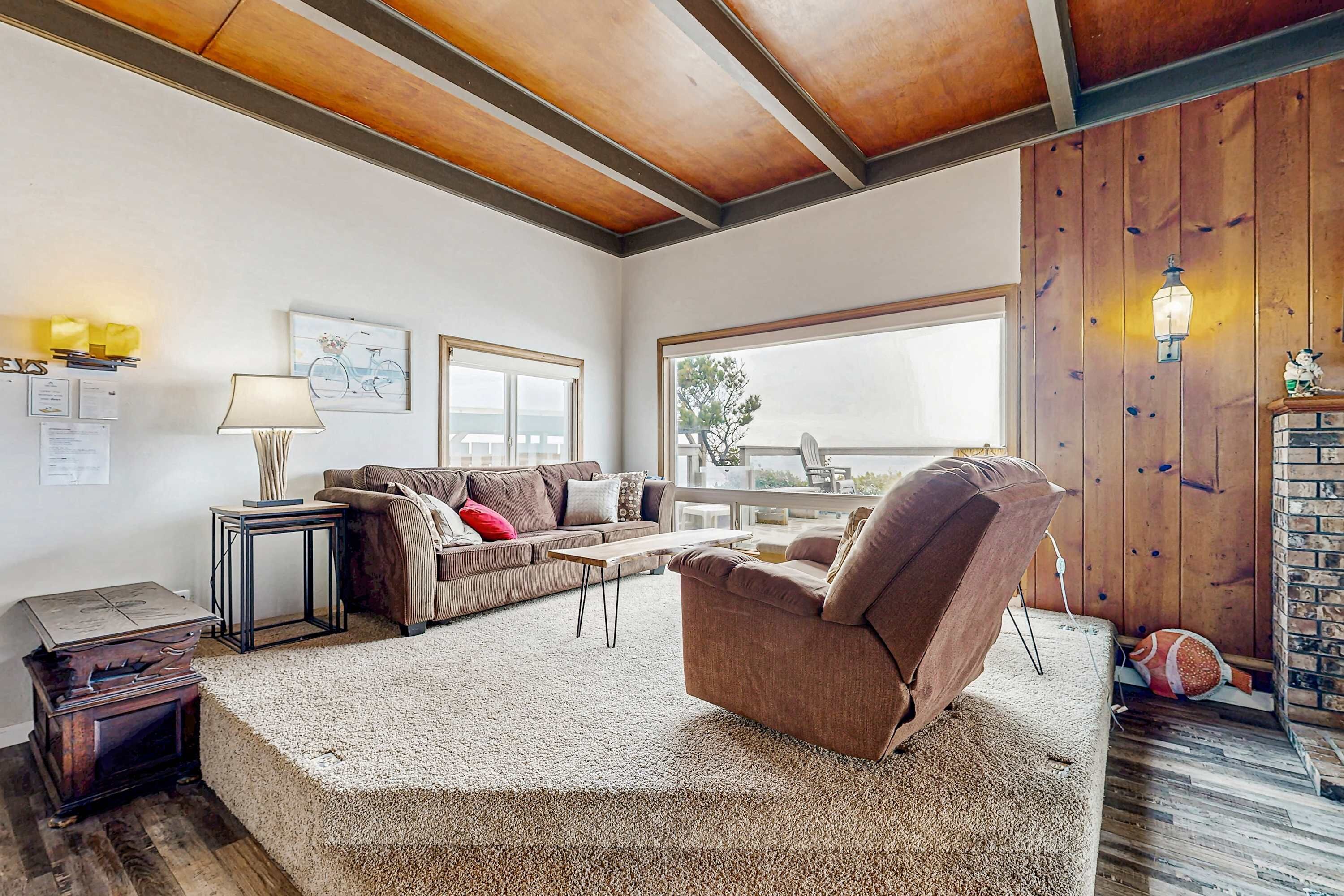 Una sala de estar acogedora con techo de madera, un sofá, un sillón, una mesita y una lámpara.