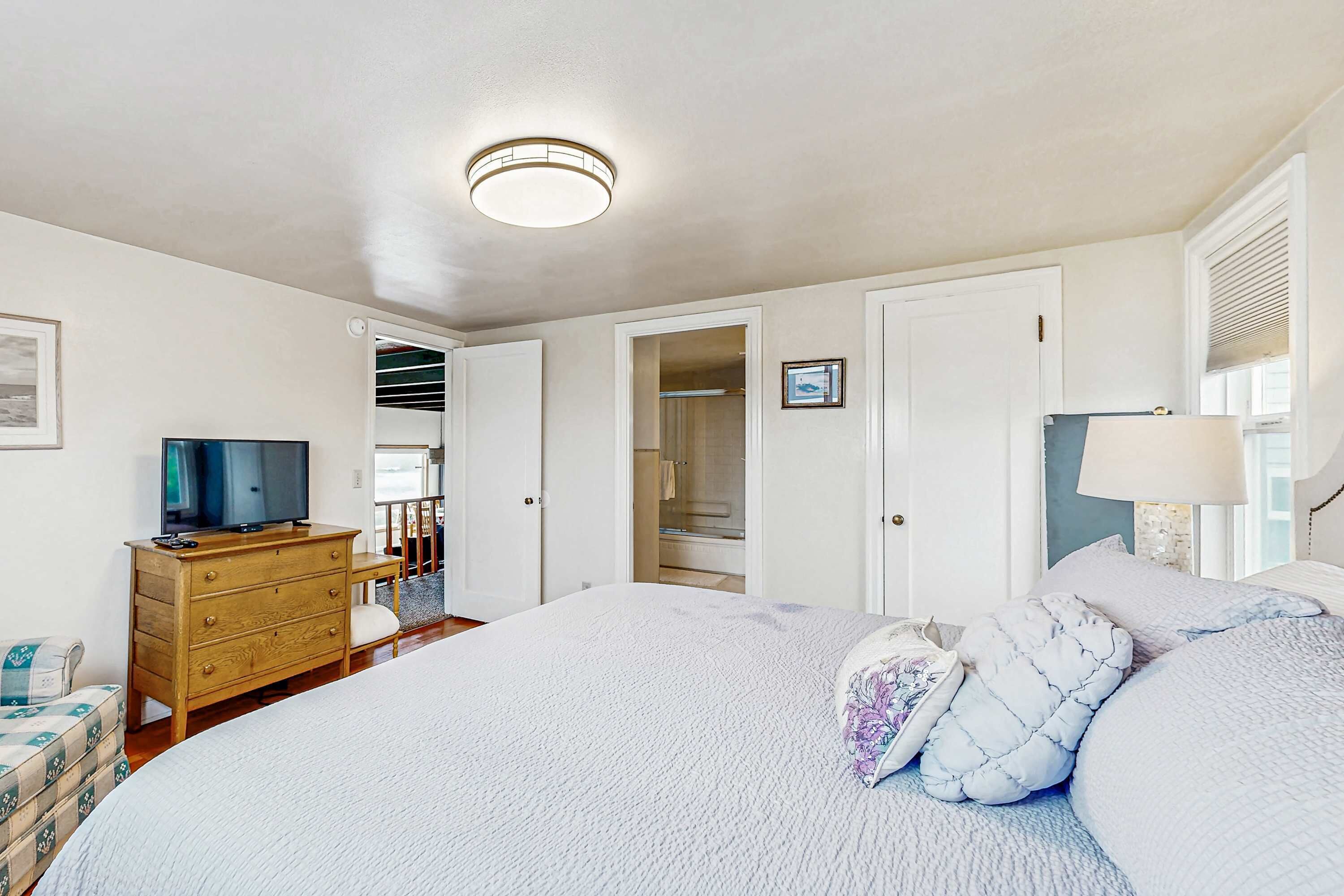 Une chambre à coucher avec un grand lit, une commode en bois, une télévision et un placard.