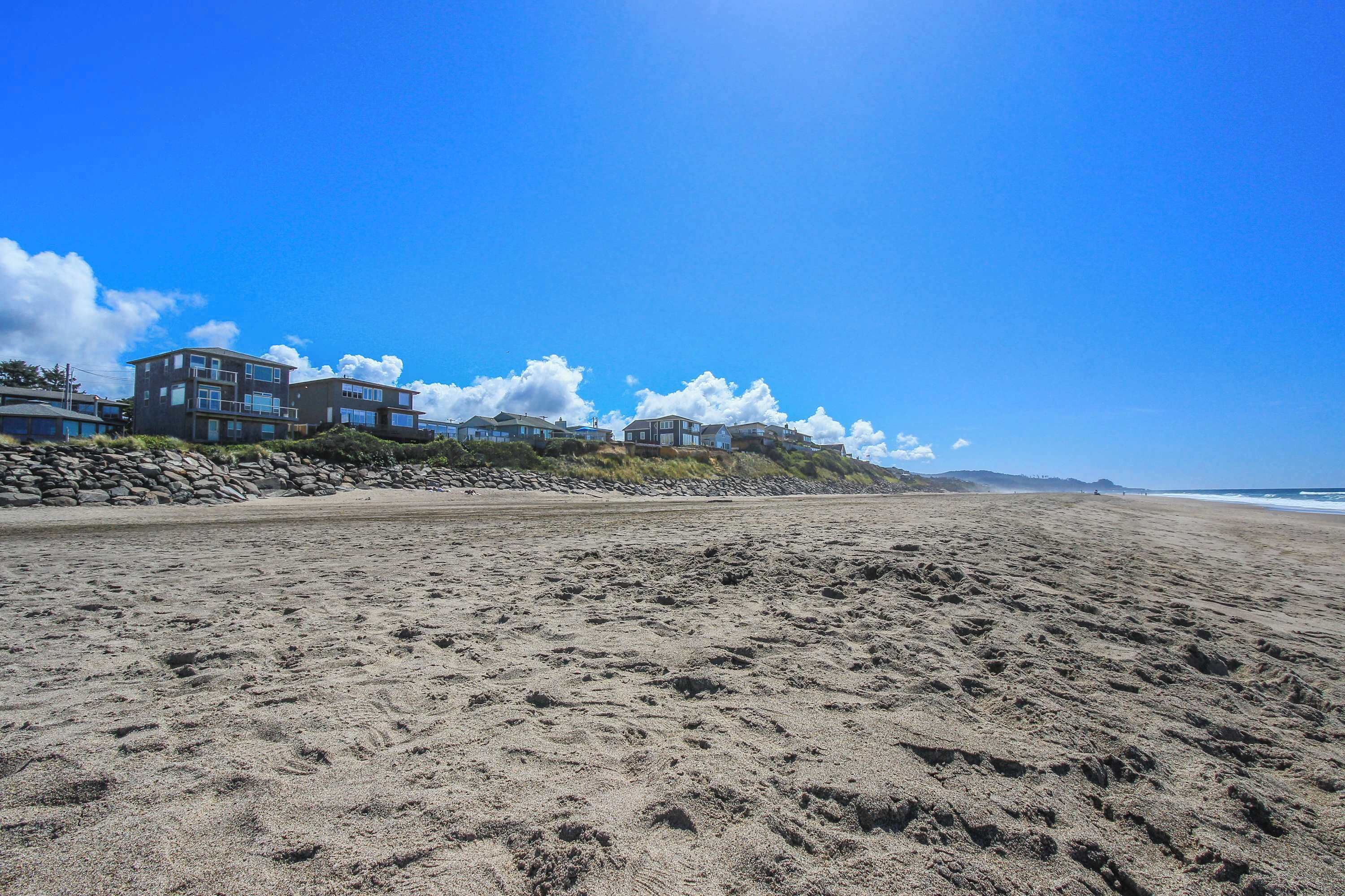 Een strand met een rij moderne huizen, een heldere lucht en een zandstrand.