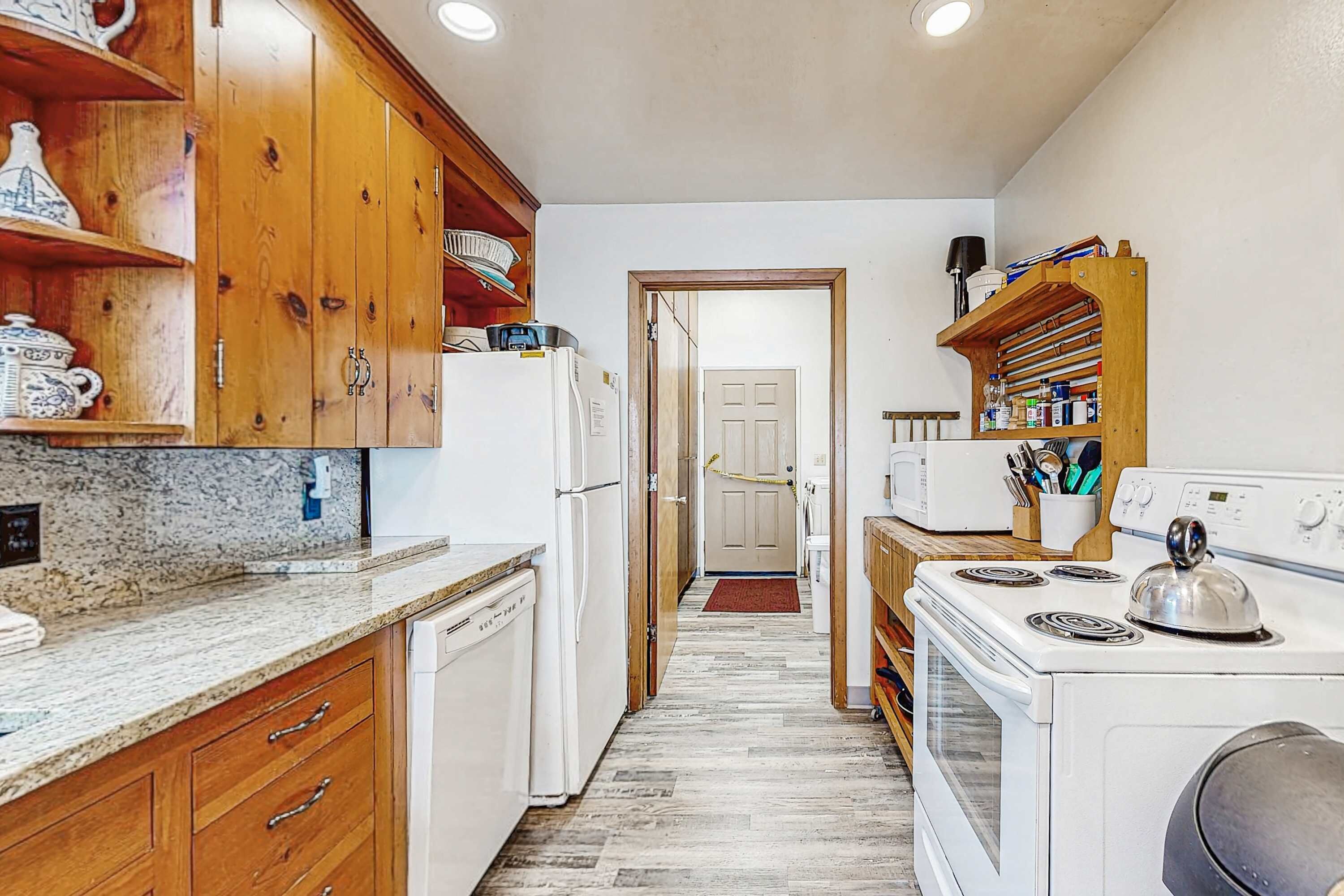 A kitchen with wooden cabinets, a refrigerator, a microwave, and a stove.