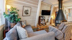 A cozy living room with a sofa, a bookshelf, a large plant, and a fireplace. - Fun and Unforgettable Beach House Dog friendly with a Great Location (Gleneden Beach)