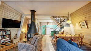 A cozy living room with a fireplace, a television, and a dining area with chairs and a table. - Fun and Unforgettable Beach House Dog friendly with a Great Location (Gleneden Beach)