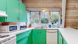 A compact kitchen with green cabinets, white countertops, and a window providing natural light. - Fun and Unforgettable Beach House Dog friendly with a Great Location (Gleneden Beach)