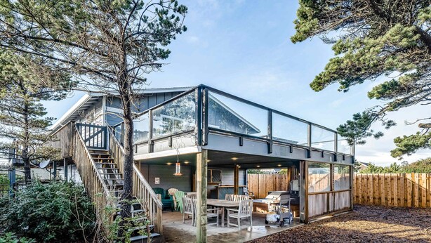 Una casa moderna con extensión de vidrio, mobiliario exterior y zona de barbacoa.