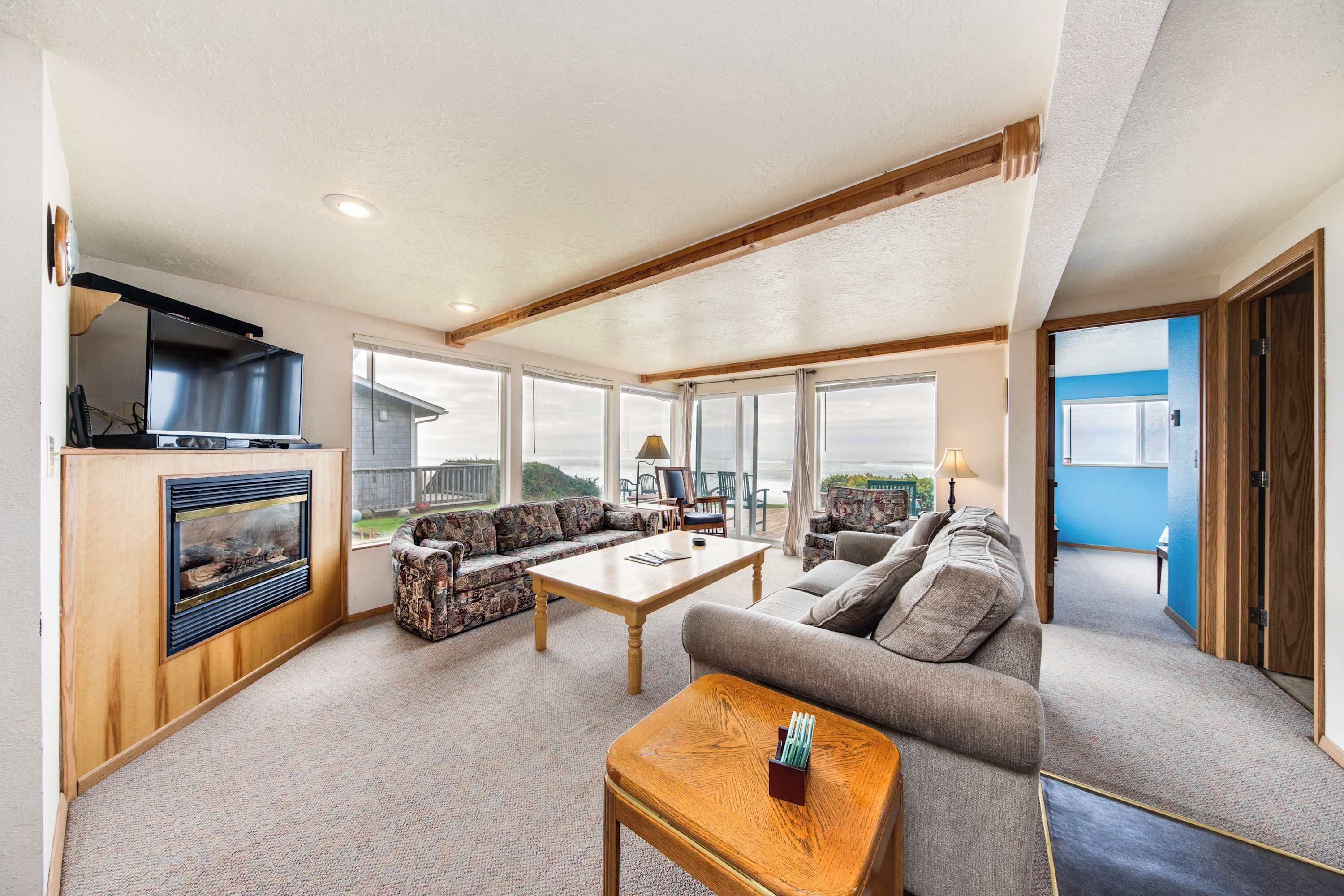 A spacious living room with a fireplace, a large TV, and a sofa.