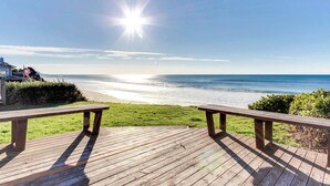 Eine Holzterrasse mit Bänken mit Blick auf einen Strand.