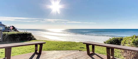 Una terraza de madera con bancos que da a una playa.