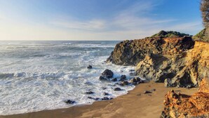 Un paisaje costero con un acantilado rocoso y una playa de arena.