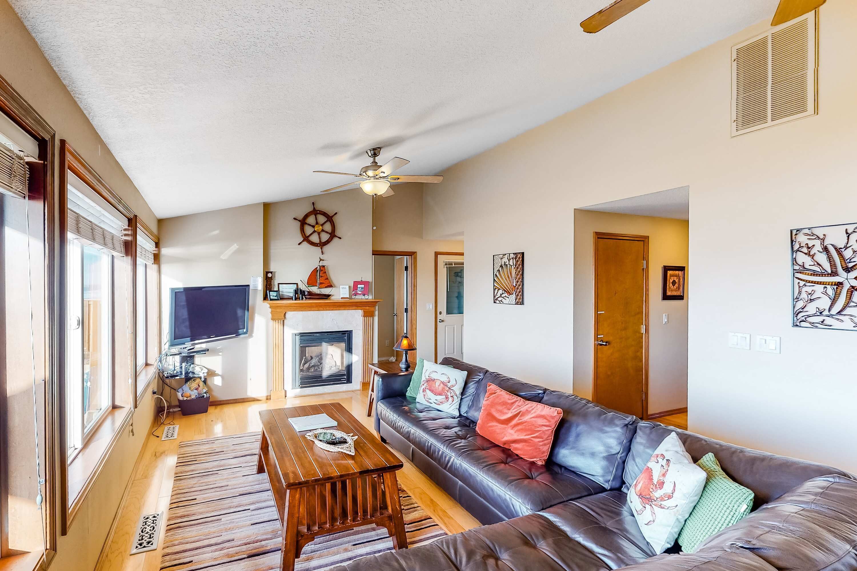 A living room with a fireplace, leather sofa, wooden coffee table, and a television.