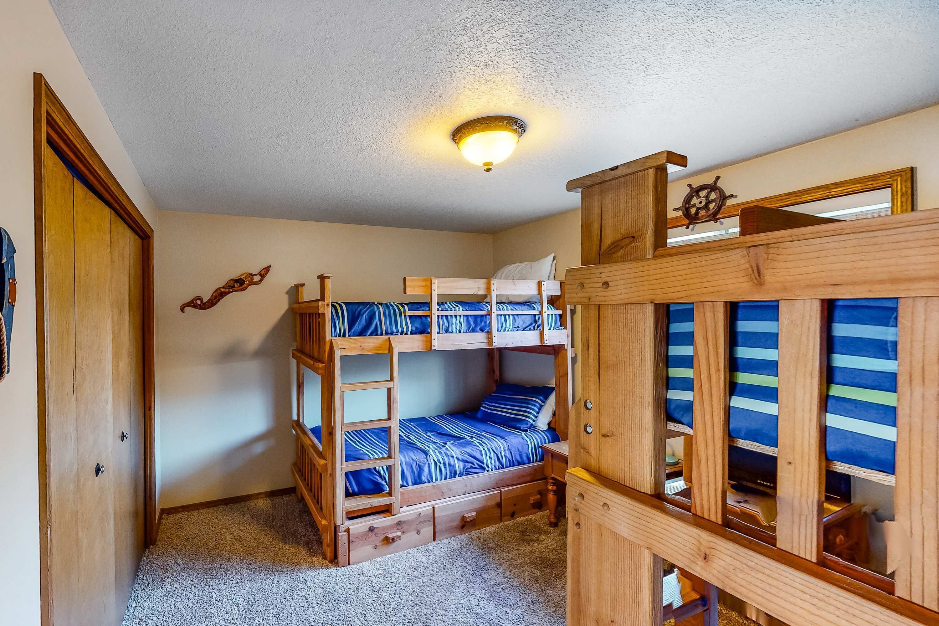 A bunk bed room with a wooden wardrobe and a ceiling light fixture.