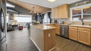 Een moderne keuken met houten kastjes, een centraal eiland en een geïntegreerde vaatwasser.