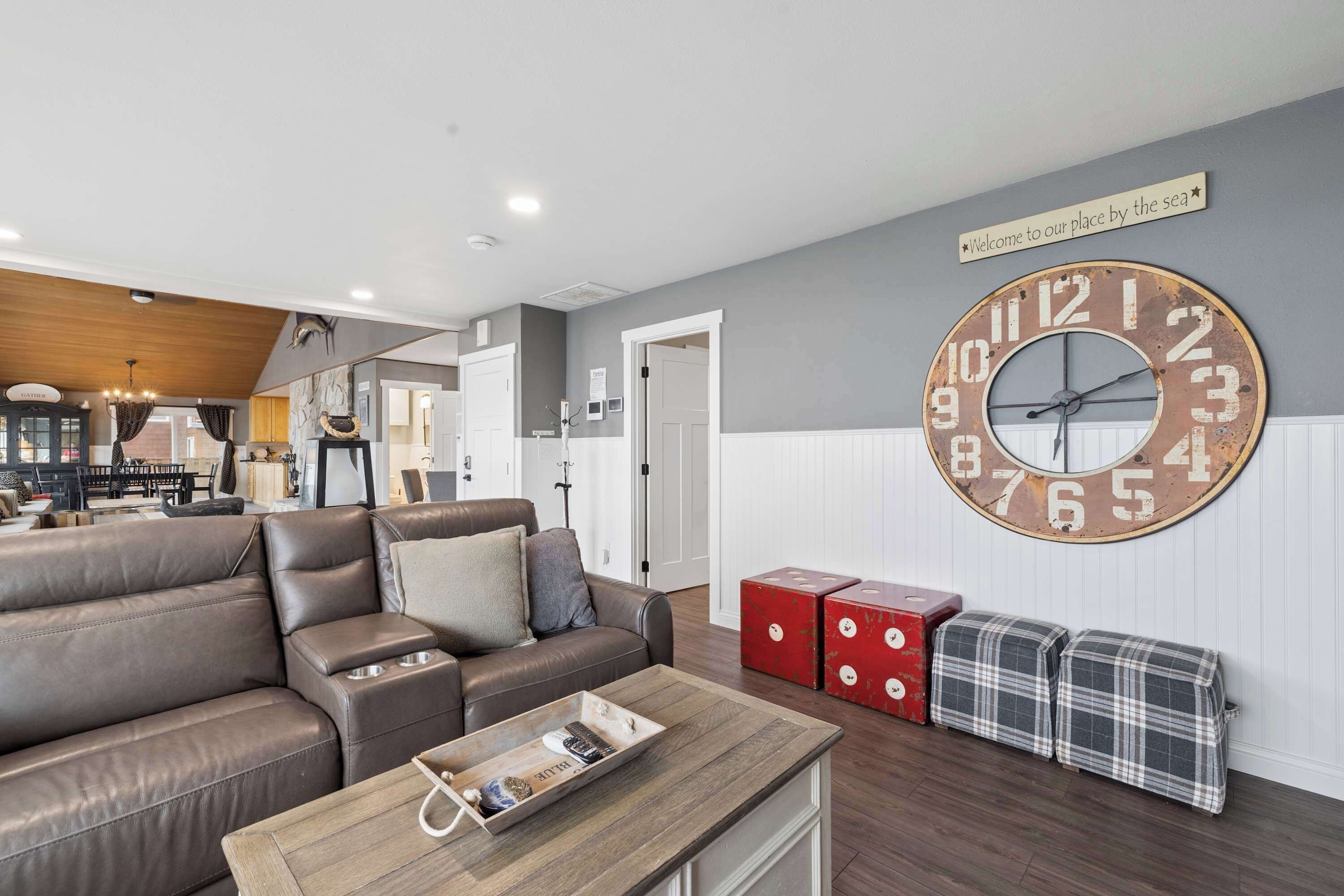 A living room with a large wall clock, a sofa, a coffee table, and a sign above the clock.