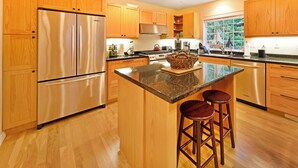 Une cuisine moderne avec des meubles en bois, des appareils en acier inoxydable et un îlot central doté de tabourets.