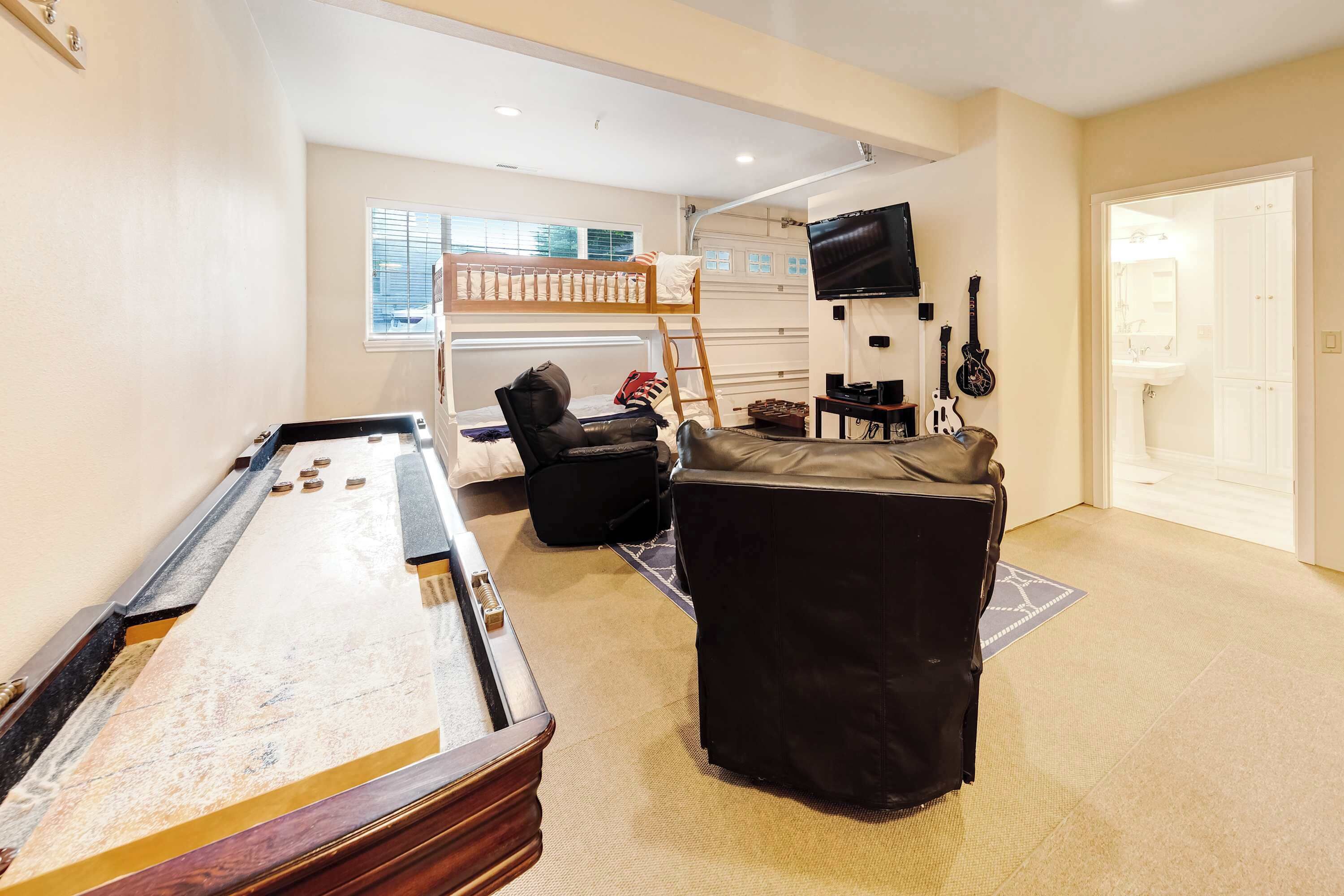 A living room with a pool table, a bunk bed, a TV, and guitars.