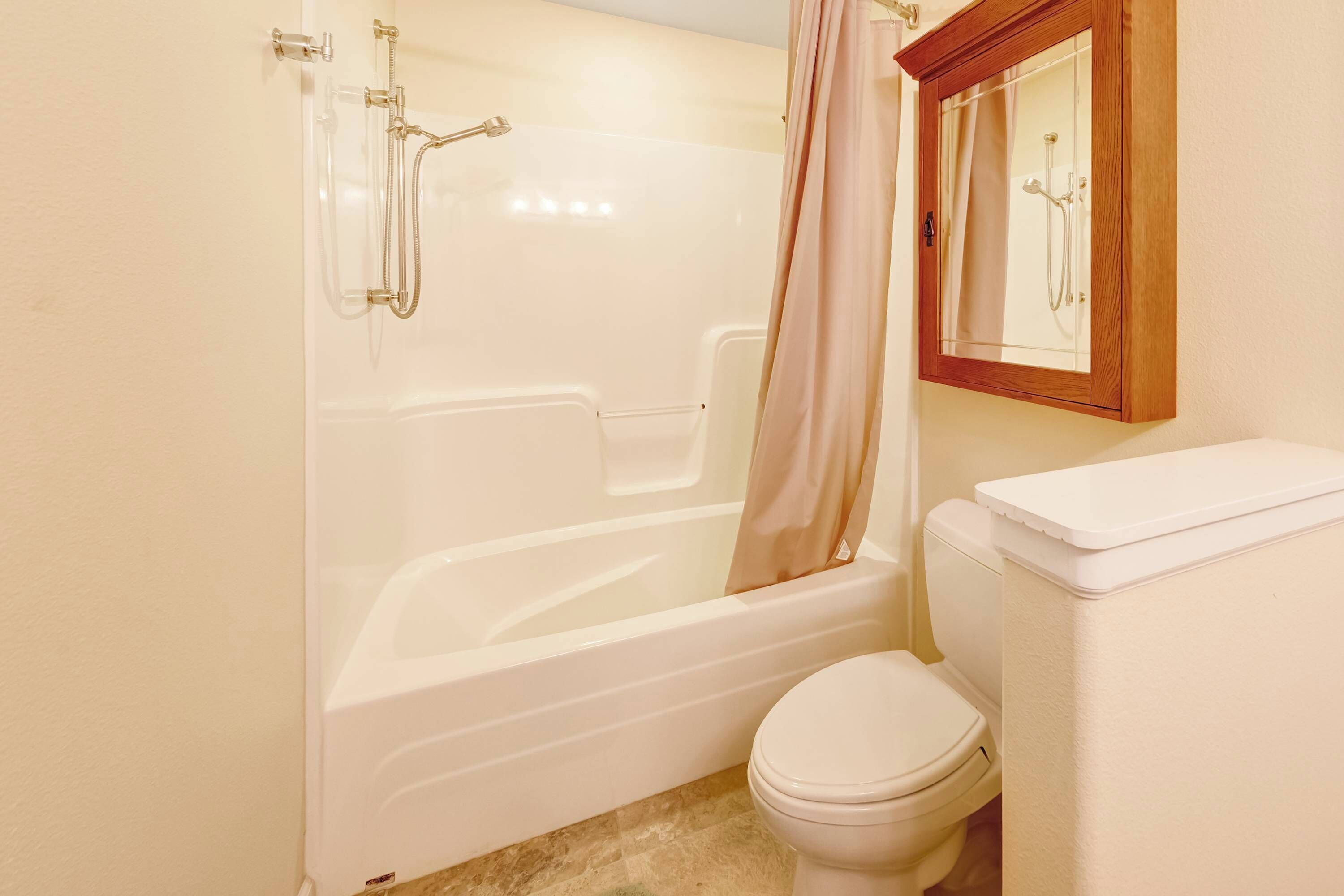 Une salle de bain avec une baignoire, des toilettes et un miroir encadré en bois.