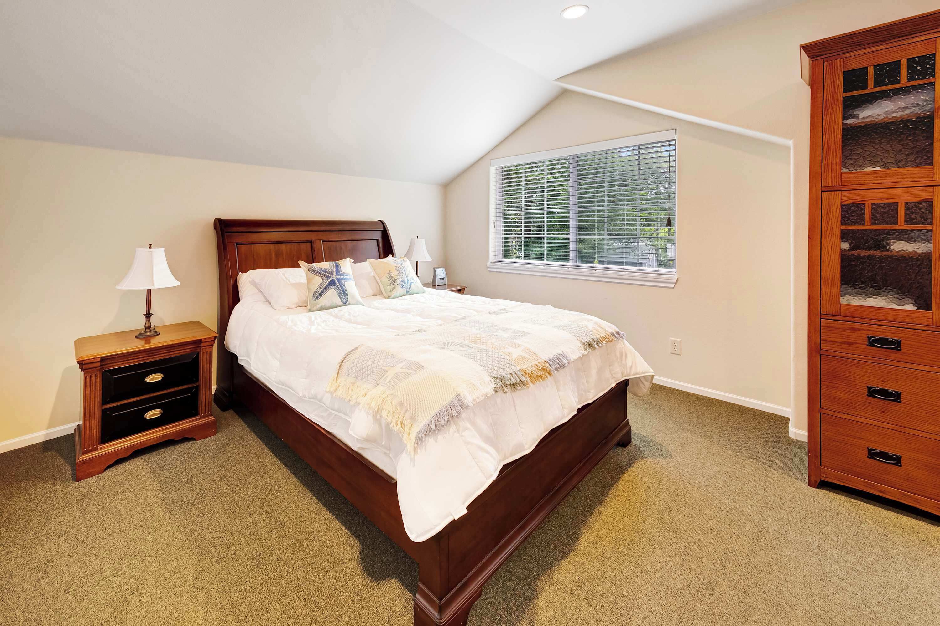 A bedroom with a wooden bed, a nightstand with drawers, a lamp, and a built-in wooden cabinet.