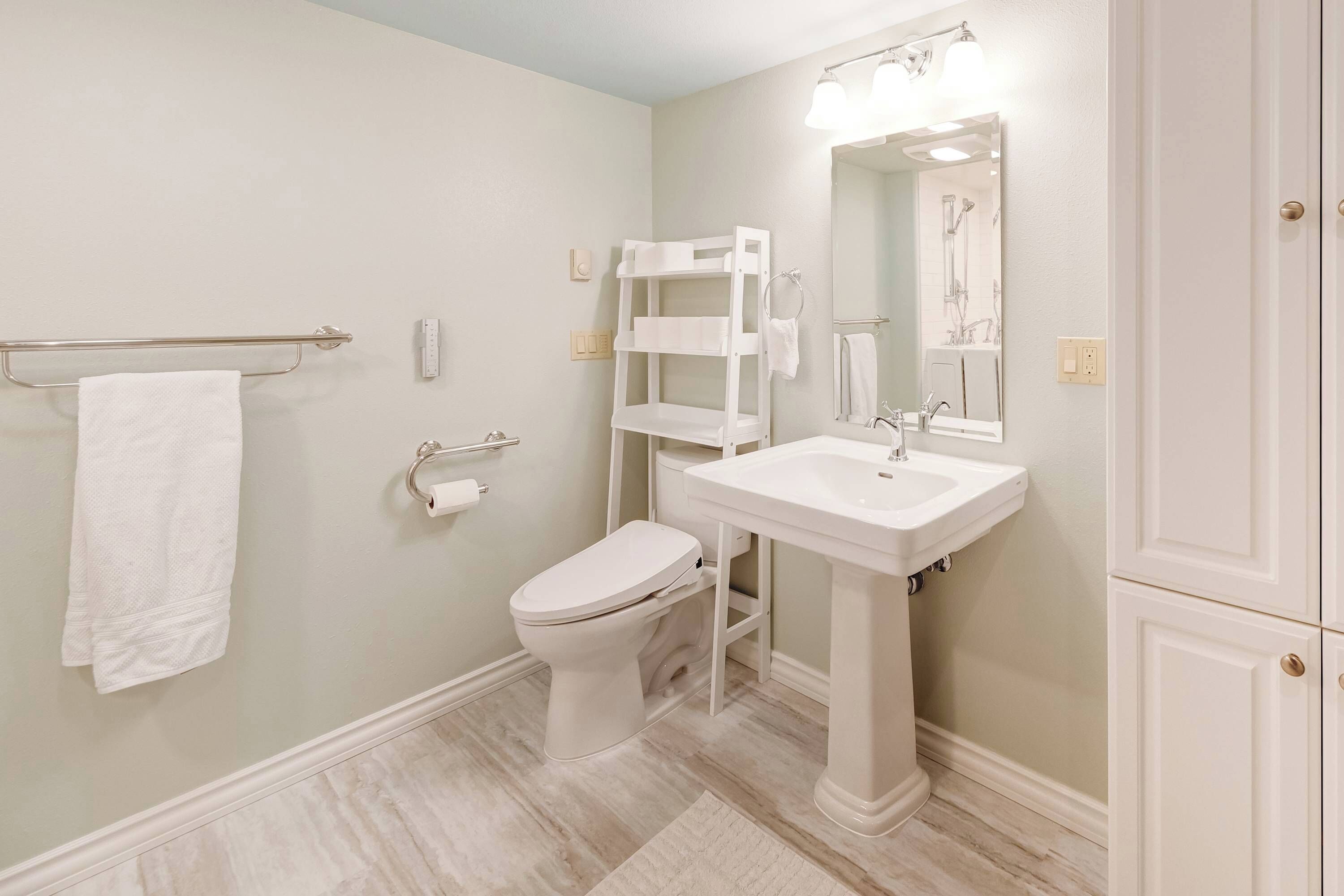 Une salle de bain équipée de toilettes, d’un lavabo et d’un porte-serviettes.