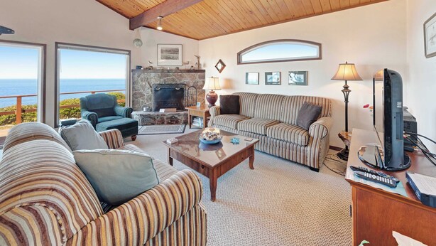 Una amplia sala de estar con chimenea de piedra, sofás a rayas, una mesa de centro y un televisor.