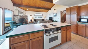 Una cocina con armarios de madera, una isla central con estufa y una chimenea de piedra.