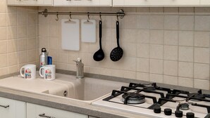 A kitchen with a gas stove, a sink, and hanging utensils. - San Giovanni prestige flat by RHR (Roma)