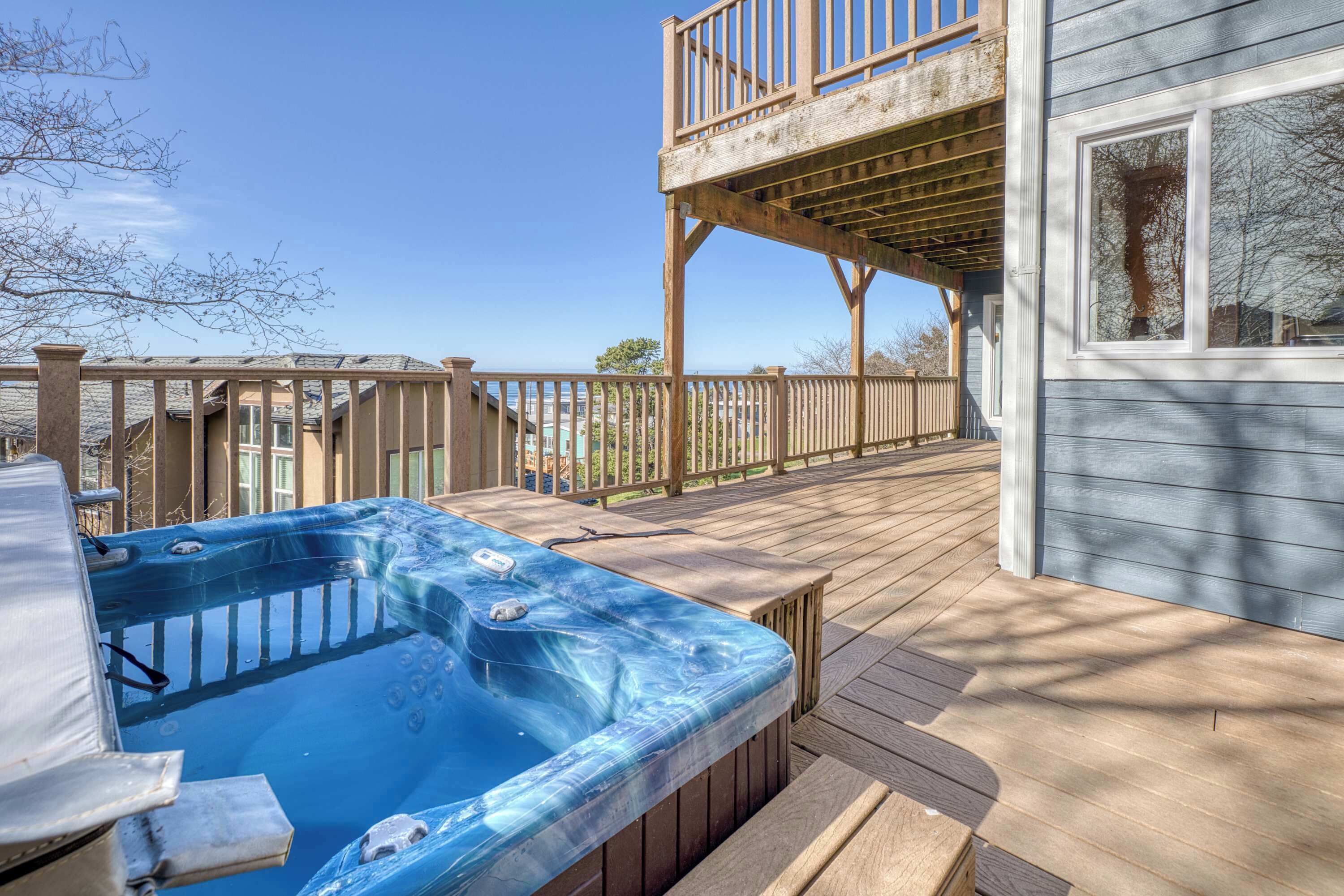 A hot tub on a wooden deck with a wooden railing and a building in the background.