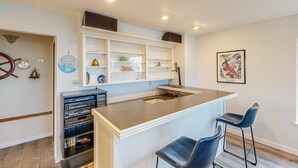 A kitchen with a bar area, white cabinetry, and a clock on the wall. - Cozy house close to beach hot tub and ocean views (Lincoln City)