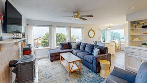 A living room with a sectional sofa, a wooden coffee table, a fireplace, and a television mounted on the wall. - Cozy house close to beach hot tub and ocean views (Lincoln City)