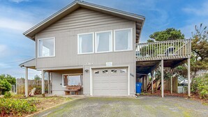 A two-story house with a garage, a covered porch, and a small deck. - Cozy house close to beach hot tub and ocean views (Lincoln City)