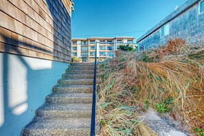 A staircase leading up to a building with a modern design, a clear sky, and a view of a residential area. - Elegant Condo with Beautiful Ocean Views and Nearby Beach Access (Lincoln City)