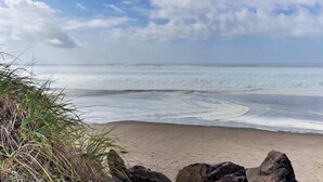 Una spiaggia con onde, cielo sereno e vegetazione.