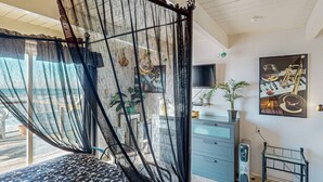 Una camera da letto con un letto, una TV, un termosifone e un quadro appeso al muro.