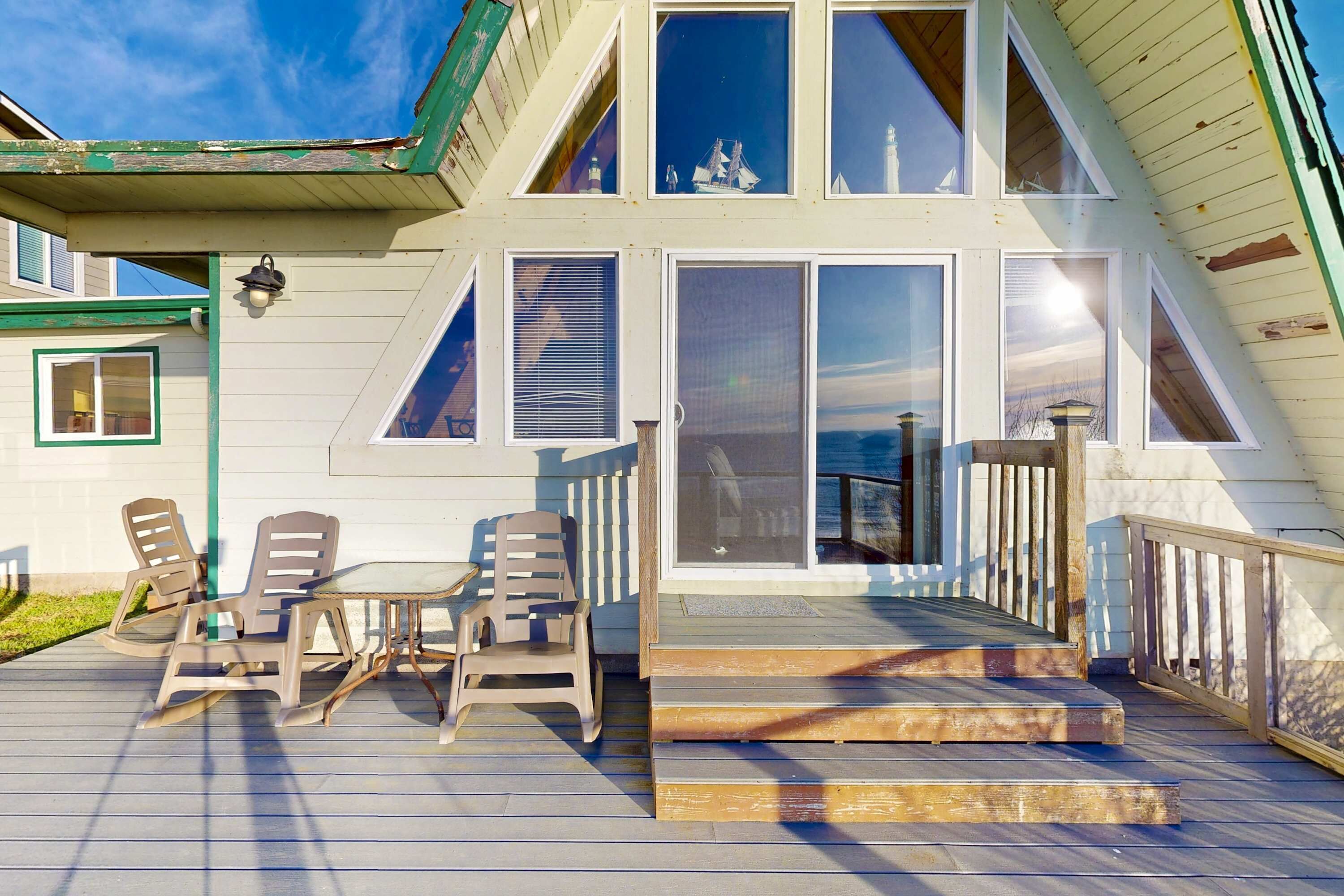 A two-story house with a deck, a sliding glass door, and a small outdoor table with chairs.