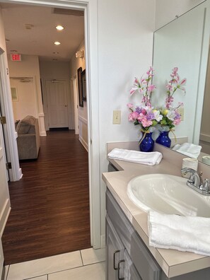 A modern bathroom with a large sink, two blue vases with flowers, and a mirror reflecting the room.