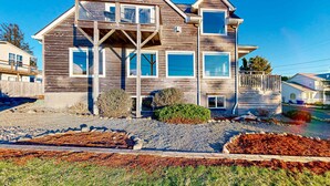Une maison à deux étages, avec une façade en bois, de nombreuses fenêtres et un porche à l’avant.