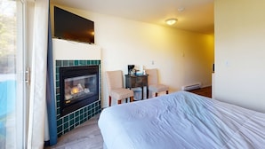 A hotel room with a bed, a fireplace, two chairs, and a small table with a coffee maker. - Lower Level Studio with Ocean Views and Easy Beach Access Dog Friendly (Lincoln City)