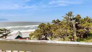 Vista costera con playa, árboles y un edificio de techo verde.