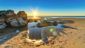 Une plage avec des rochers et une mer calme sous un ciel dégagé.