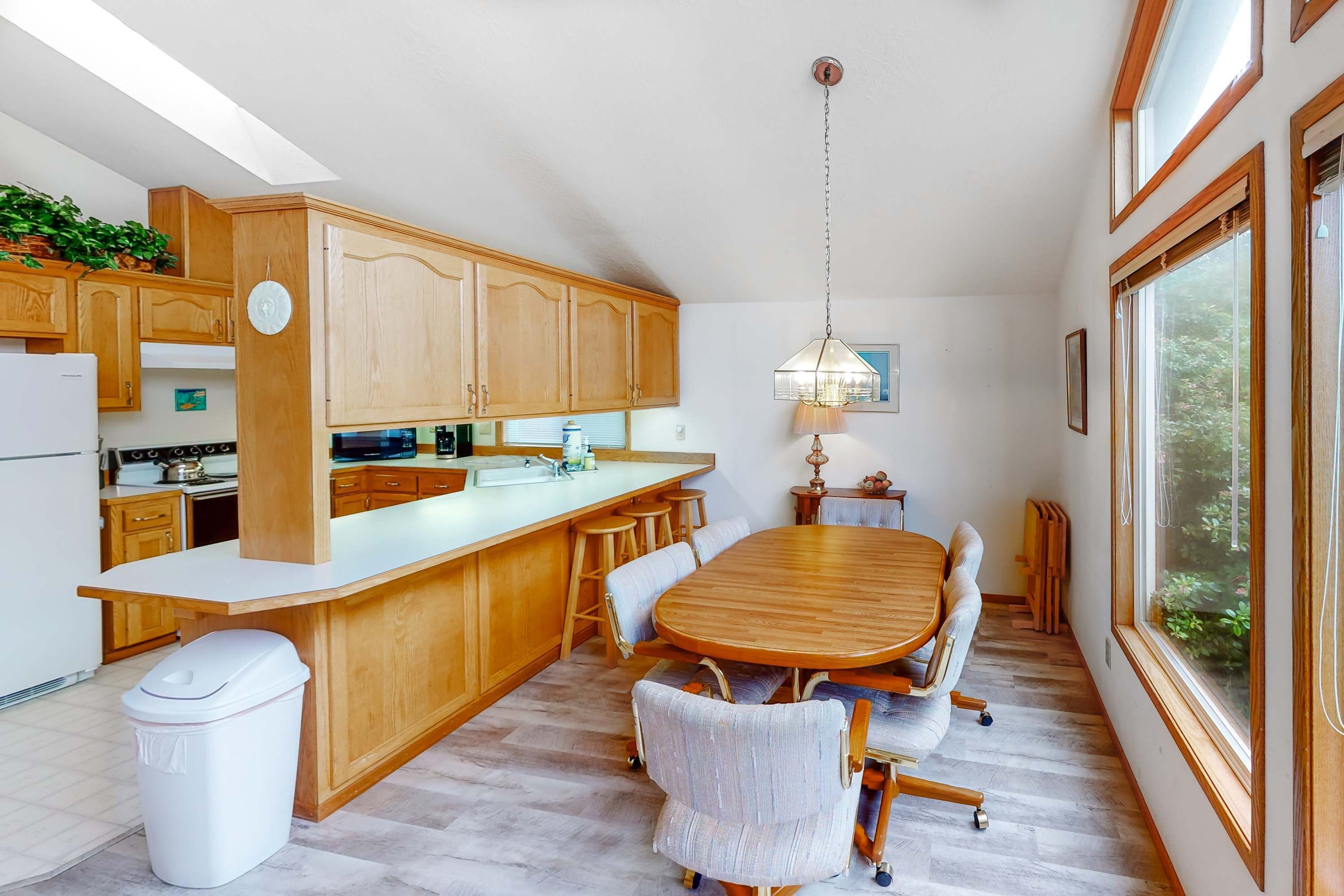 Una cocina moderna con armarios de madera, una isla grande y una zona de comedor con mesa y sillas de madera.