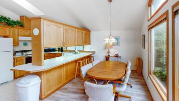 Una cocina moderna con armarios de madera, una isla grande y una zona de comedor con mesa y sillas de madera.